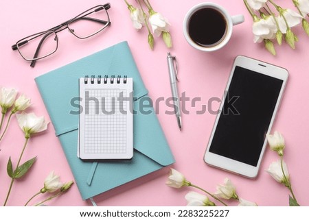 Notebooks, coffee and a smartphone and beautiful eustoma flowers on a delicate pink background. top view