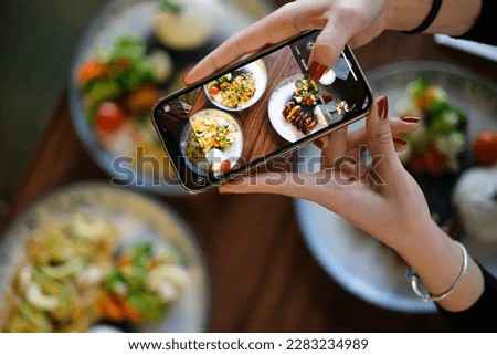 Top view woman taking photo of food with phone in hand. Food photography with phone. Social media photography. Royalty-Free Stock Photo #2283234989