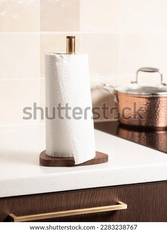 Paper towels on a holder. Stylish bright kitchen and kitchen utensils in the background. Royalty-Free Stock Photo #2283238767