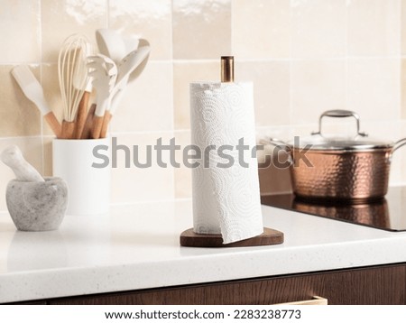 Paper towels on a holder. Stylish bright kitchen and kitchen utensils in the background. Royalty-Free Stock Photo #2283238773
