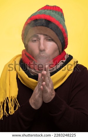A man in warm clothes and several hats warms himself during the cold and steam comes from his mouth Royalty-Free Stock Photo #2283248225