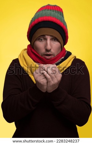 The man is very cold and rubs his hands from the cold and cold in warm clothes and a scarf Royalty-Free Stock Photo #2283248237