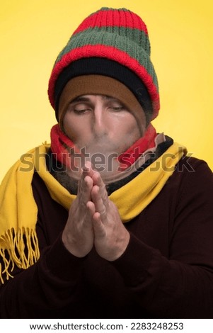 A man in warm clothes and several hats warms himself during the cold and steam comes from his mouth Royalty-Free Stock Photo #2283248253