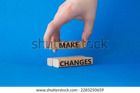 Make changes symbol. Wooden blocks with words Make changes. Beautiful blue background. Businessman hand. Business and Make changes concept. Copy space.
