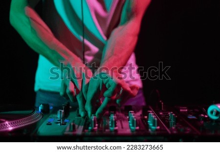 Club DJ playing music on stage. Close up photo of professional disk jokey mixing musical tracks from vinyl records with sound mixer Royalty-Free Stock Photo #2283273665
