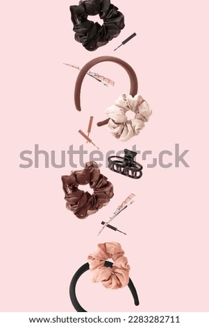 Hair accessories floating in the air against pastel pink background. Rubber band, hairclip, hairpin and headband levitating. Fun women fashion concept.