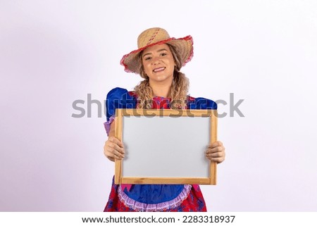 Young woman dressed in typical festa junina outfit holding a blank mockup with free space for text