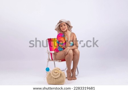 Young woman on vacation sitting on beach chair and summer outfit on background for clipping. Holiday and travel promotion