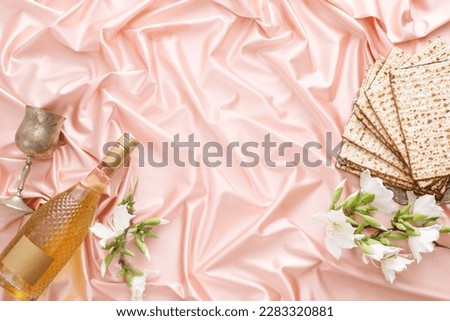 Matzo with white flowers, wine and a glass on a pale pink background. Pesach celebration concept (jewish Passover holiday)
