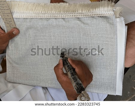 man writing on the prayer rug for gift in medina, text translation: samnah