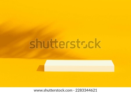 White empty platform, podium on yellow background and tree shadows