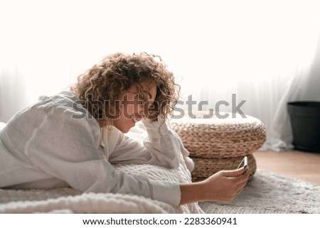 Content young woman touching head and using smartphone on bed