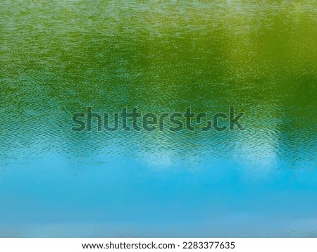 The reflection of the blue sky above the clear water surface 