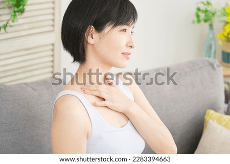 Asian woman massaging her breasts in the living room Royalty-Free Stock Photo #2283394663