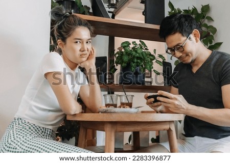 Bad asian couple date of man addicted to mobile game and woman gets mad. Royalty-Free Stock Photo #2283396877