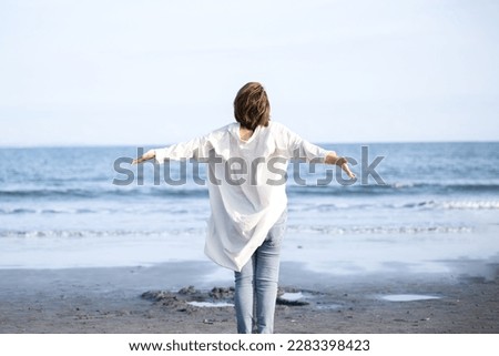 Woman taking deep breaths and stretching on sandy beach Stress free Royalty-Free Stock Photo #2283398423