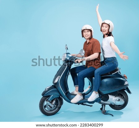 Young Asian couple ride scooter on background Royalty-Free Stock Photo #2283400299