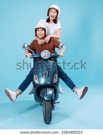 Young Asian couple ride scooter on background Royalty-Free Stock Photo #2283400321