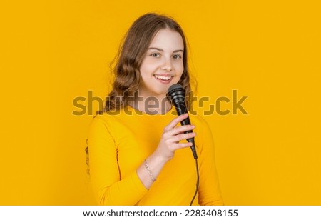 happy teen girl performer with microphone on yellow background Royalty-Free Stock Photo #2283408155