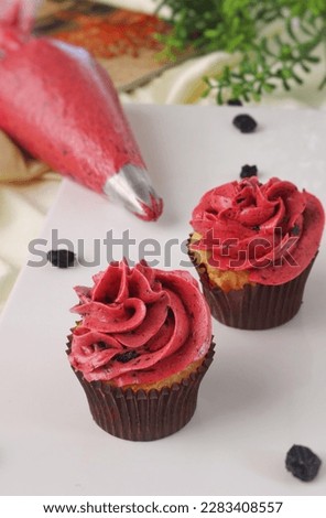 Rasberry cupcake on a platter with Rasberry frosting on a piping bag