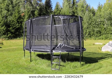 Trampoline with safety net in the garden Royalty-Free Stock Photo #2283432679