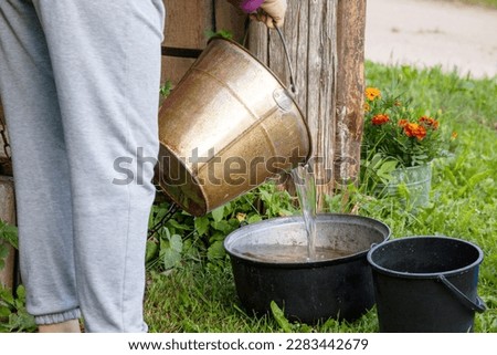 A woman is watering a bucket of water.