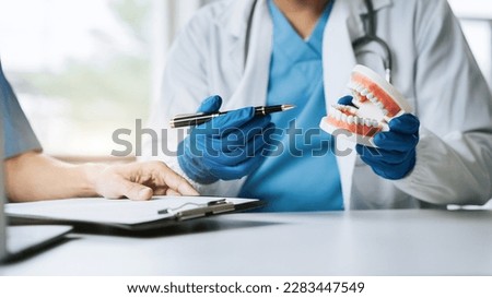 Young Male dentist holding tooth model. Royalty-Free Stock Photo #2283447549