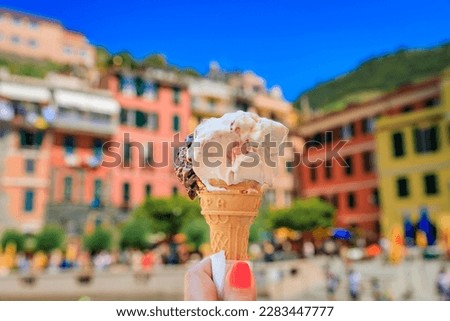 Hand holding an artisanal gelato, a view of traditional colorful houses in old town of Vernazza in Cinque Terre on the Mediterranean Sea, Italy Royalty-Free Stock Photo #2283447777