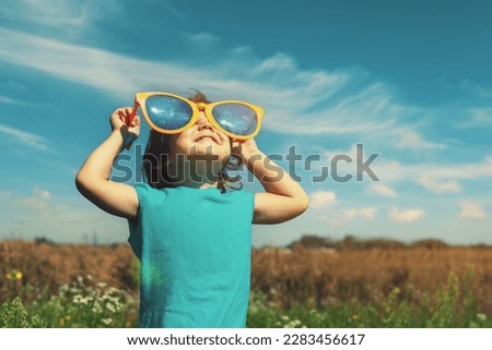 Little girl with big sunglasses enjoys sun   #uniquesself Royalty-Free Stock Photo #2283456617