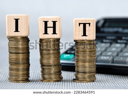 IHT (Inheritance Tax) - acronym on wooden cubes on the background of coins and calculator. Business and finance concept