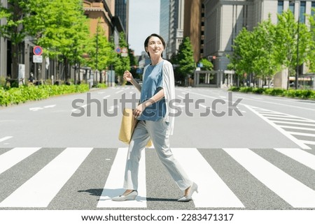 Young businesswoman crossing a crosswalk Royalty-Free Stock Photo #2283471317