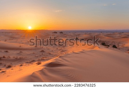 Sunset over the sand dunes in the desert. Arid landscape of the Sahara desert Royalty-Free Stock Photo #2283476325