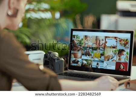 female photographer with laptop and photo camera viewing photos in modern office.