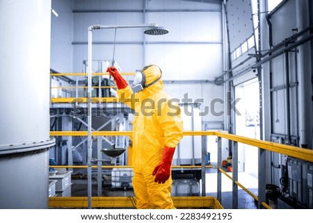 Safety at work. Occupational health and safety regulations. Worker in chemicals production plant taking a shower after accident washing away the acid. Royalty-Free Stock Photo #2283492195