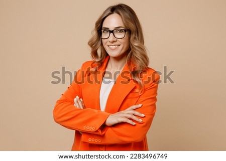 Young successful employee business woman corporate lawyer wear classic formal orange suit glasses work in office look camera hold hands crossed folded isolated on plain beige color background studio Royalty-Free Stock Photo #2283496749