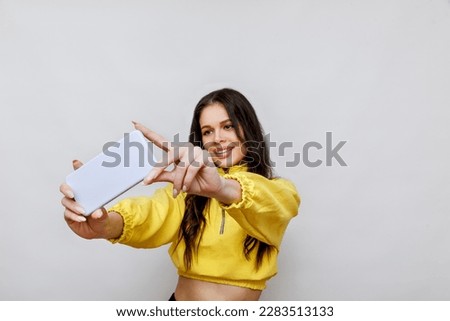 Portrait of smiling girl having video-call with lover holding smart phone in hand shooting selfie on front camera