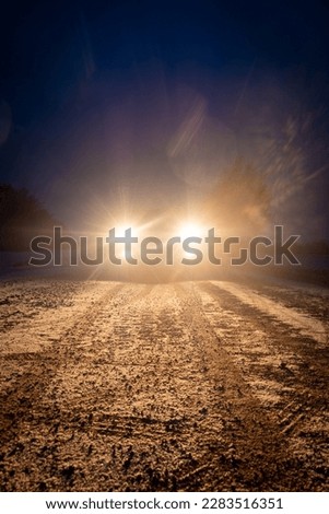 Yellow headlight and dirtroad in the dark after snowing. Car driving on a dangerous road in dire circumstances. High quality photo Royalty-Free Stock Photo #2283516351