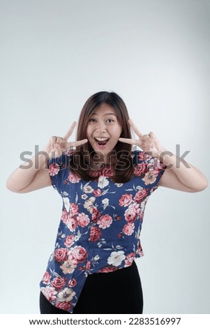 young asian woman isolated on white background smiling and showing victory sign