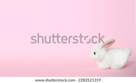 A white bunny stands cutely in the right corner of the photo against a soft pink background, with plenty of empty space to the left and above.
