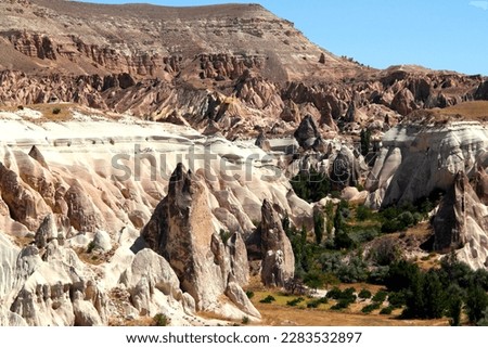 Landscape with cone-shaped mountains of the Rose Valley with the rocks of the Red Valley in the background between the towns of Goreme and Cavusin in Cappadocia, Turkey