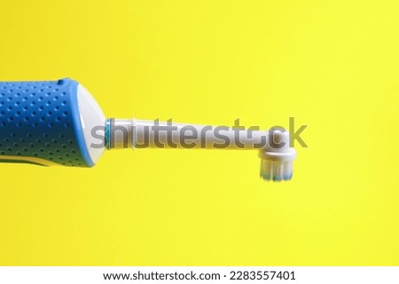 Electric toothbrush on yellow background