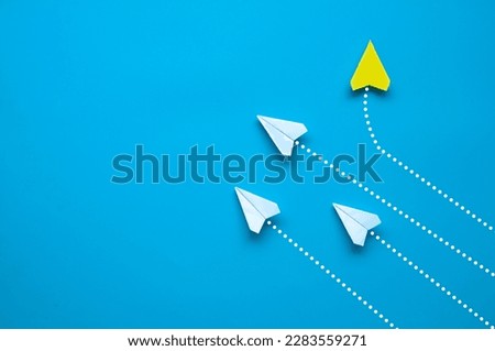 Top view of paper airplane - Yellow paper airplane origami flying to a different direction leaving other white airplanes on blue background. Leadership concept