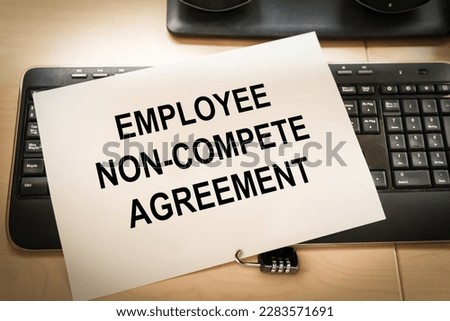 keyboard of an office computer with a piece of paper on top and a padlock, symbolizing the non compete agreement clauses Royalty-Free Stock Photo #2283571691