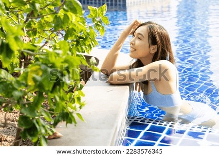Happy smiling relaxed summer woman wearing bikini swimwear in the swimming pool, concept of summer vacation, tropical travel, digital nomad taking a break, healthy lifestyle, work life balance