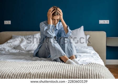 Upset depressed woman sitting on bed hold head in hands lost in thoughts thinking of problem solution. Worried devastated unhappy young female suffering from personal trouble need psychological help Royalty-Free Stock Photo #2283603139