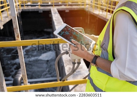 Wastewater treatment concept. Service engineer on  waste water Treatment plant and checking oxygen in water with tablet.  Wastewater treatment concept. Service engineer on waste water Treatment plant. Royalty-Free Stock Photo #2283603511