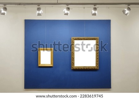 Old style vintage golden frames on the illuminated blue background on the wall. Art gallery interior 