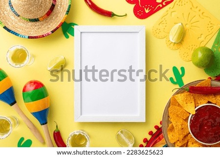 Vibrant Cinco de Mayo party concept. Mexican sombrero, colorful poncho, maracas, tequila shots, lime, chili pepper, nacho chips, salsa sauce on a bright yellow background, with empty frame for ad