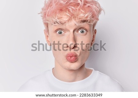 Portrait of surprised young man stares bugged eyes keeps lips rounded freckled skin reacts to something shocking news dressed casually isolated over white background. People and wonder concept