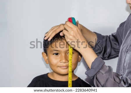young woman in a hijab measures a boy's body with a measuring tape